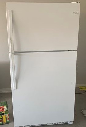 Picture of a basic white fridge in a utility space.