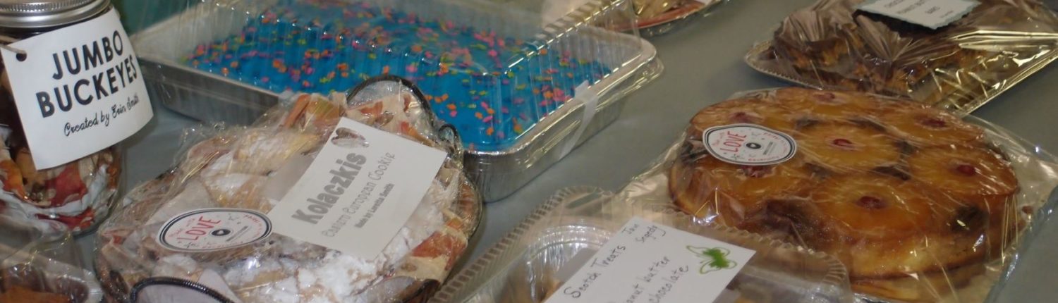 Several desserts, including buckeyes, a blue-frosted cake, and a pineapple upside down cake, are laid out on a table.